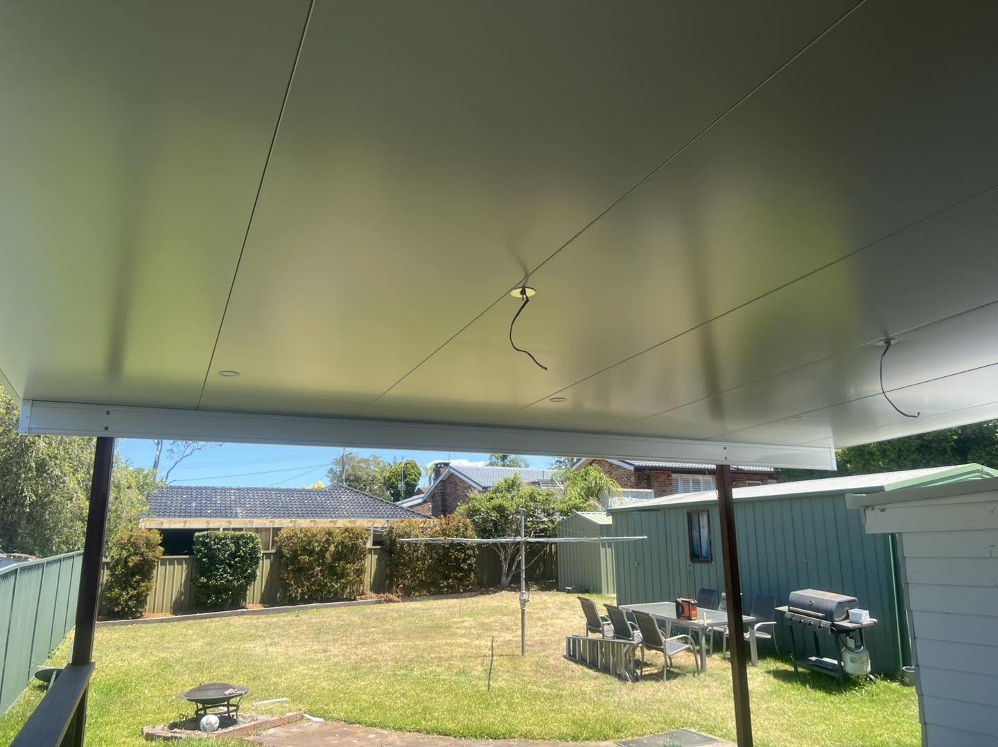 Underside of a new insulated flyover awning with downlights over a backyard