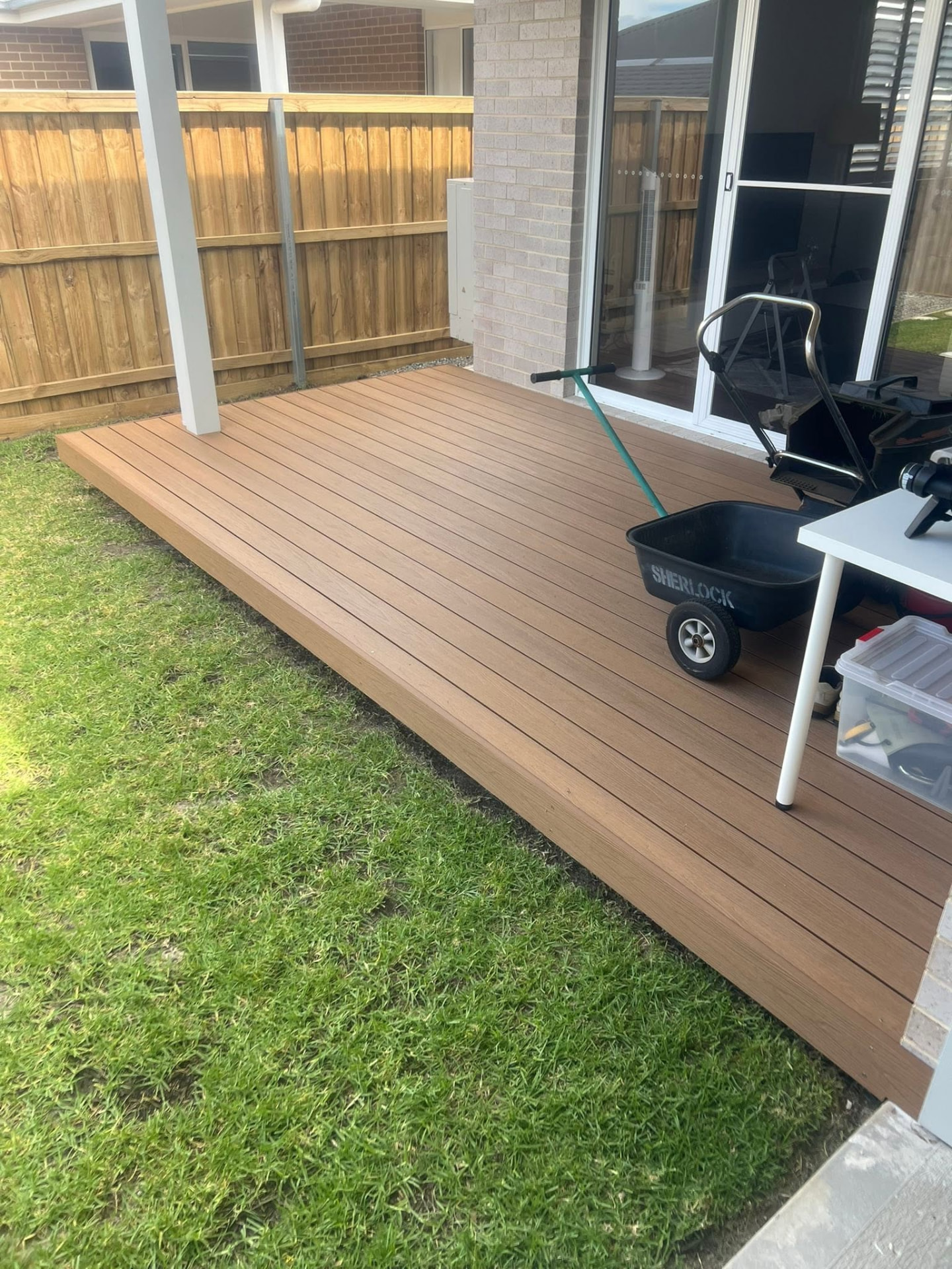 Tan composite deck built off the rear of a brick house onto a lawn