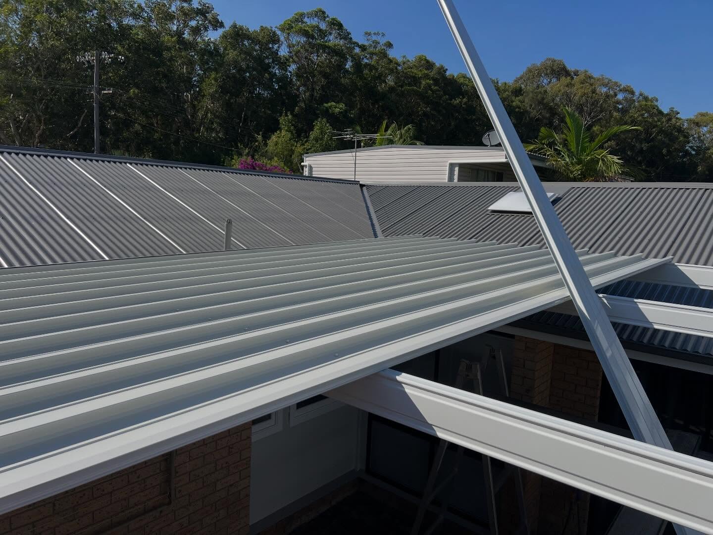 Awning roof sheeting and beams during installation above a brick house