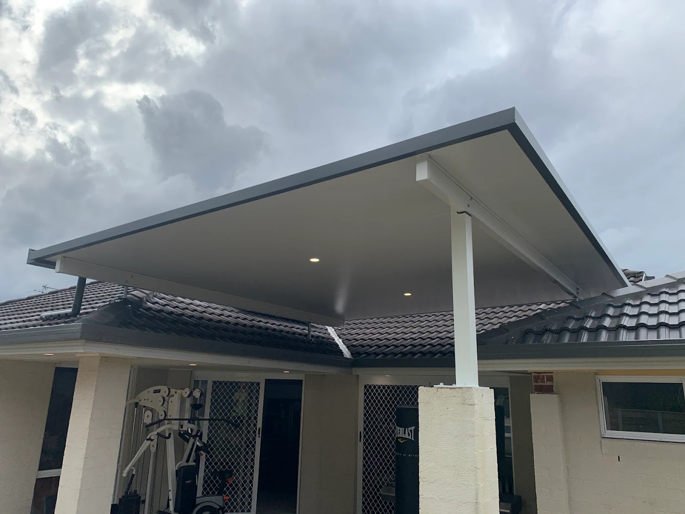 Cantilevered awning with a single post and downlights over a patio