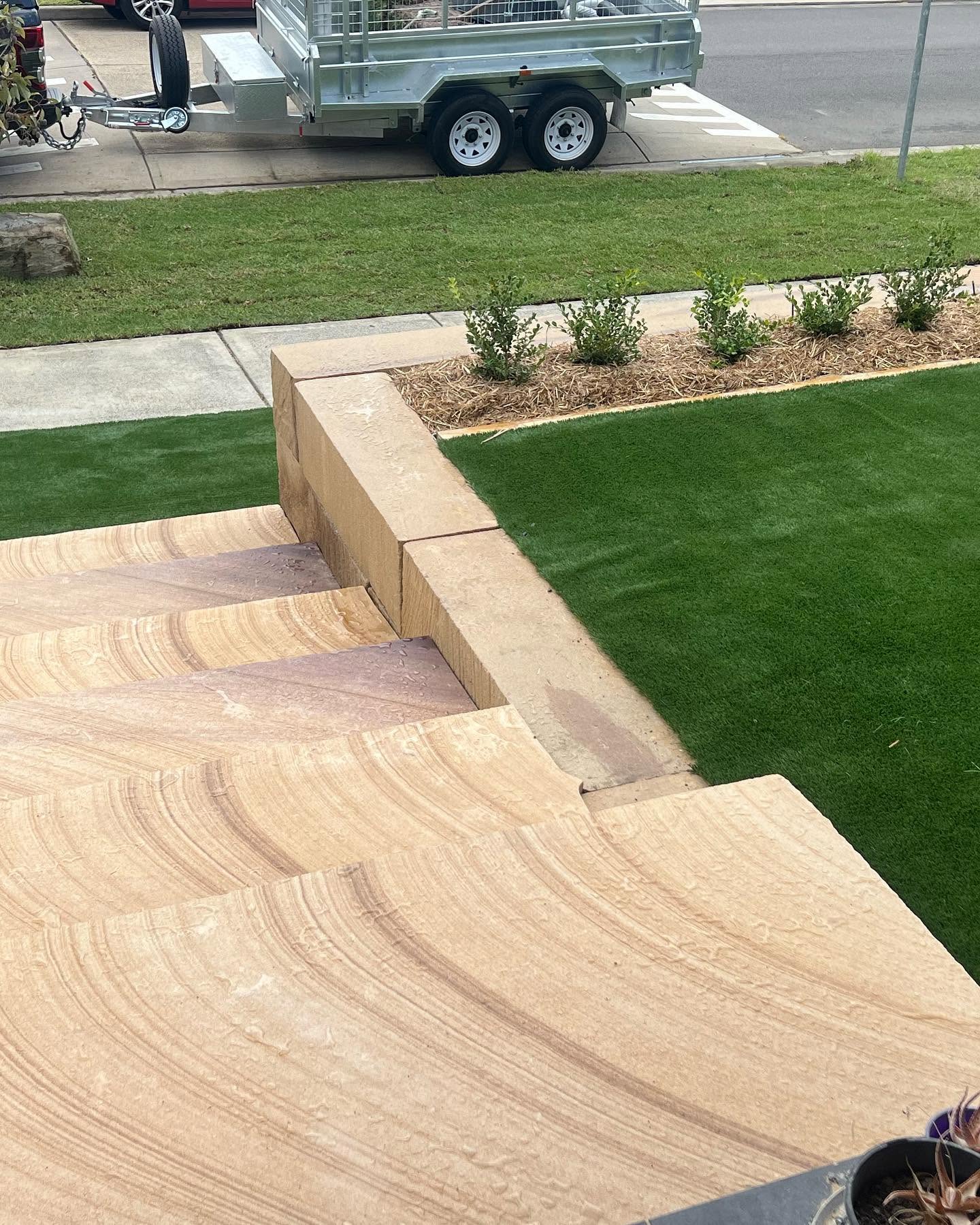 High angle view of sandstone stairs and retaining wall bordering a green lawn