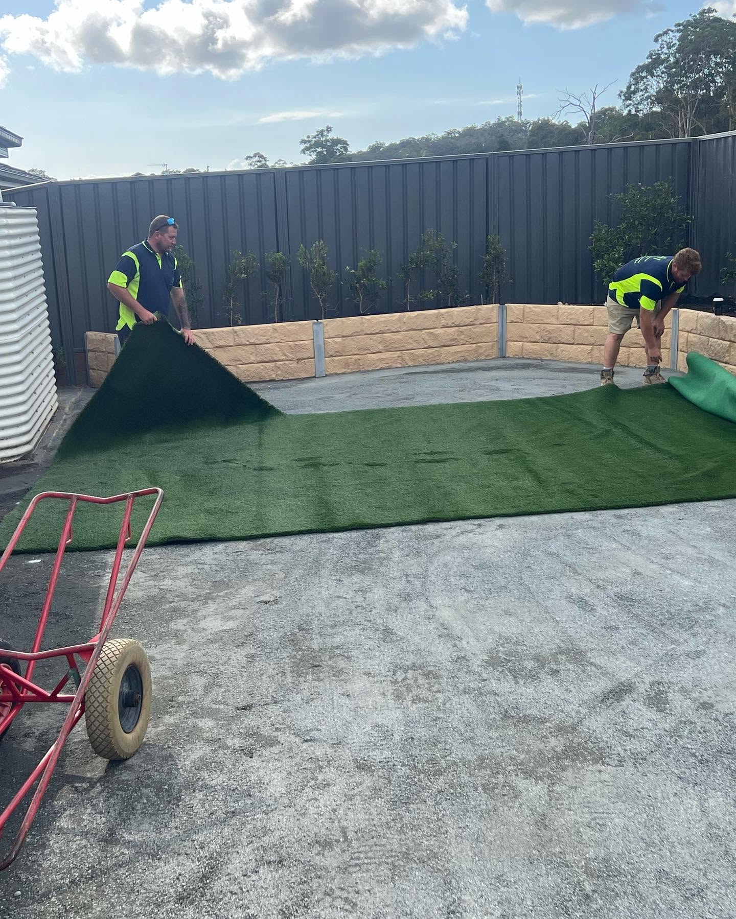 Two Kingz Construction workers laying turf in a backyard