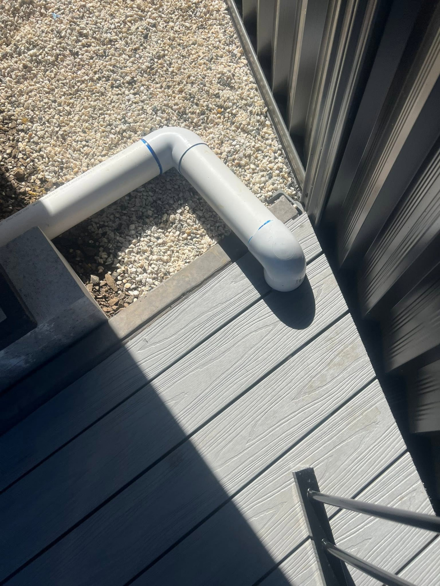 White drainage pipe installed over a grey composite deck